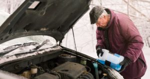 Gentleman preparign his vehicle properly for winter weather in order to avoid a car accident.